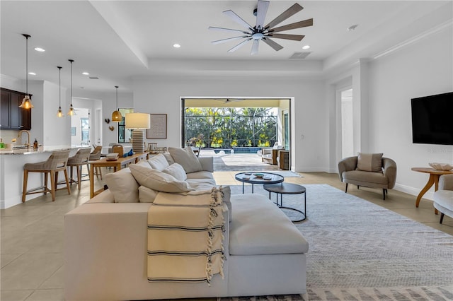 living room featuring a raised ceiling and ceiling fan