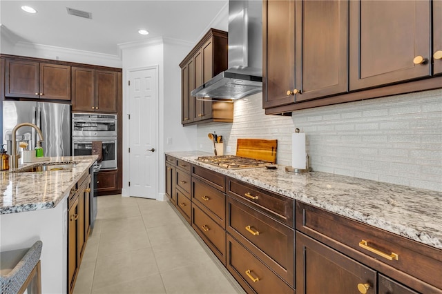 kitchen featuring light stone countertops, sink, stainless steel appliances, wall chimney range hood, and ornamental molding