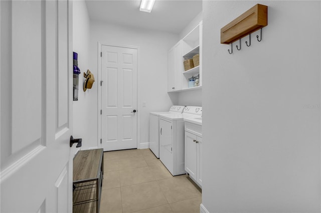 washroom with washing machine and clothes dryer, light tile patterned floors, and cabinets