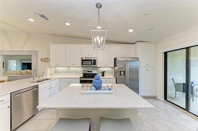 kitchen with appliances with stainless steel finishes, vaulted ceiling, sink, white cabinetry, and hanging light fixtures