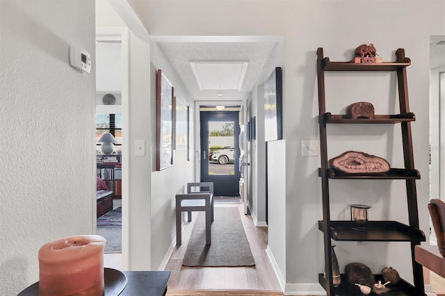 hallway featuring light wood-type flooring and a textured ceiling