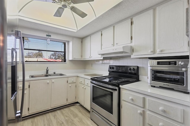 kitchen with stainless steel range with electric cooktop, white cabinets, sink, light hardwood / wood-style flooring, and ceiling fan