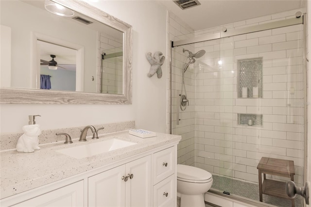 bathroom featuring a shower with door, vanity, ceiling fan, and toilet