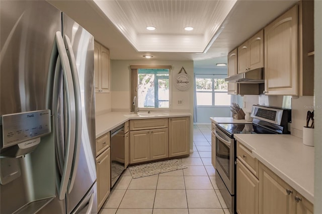 kitchen with sink, light tile patterned floors, appliances with stainless steel finishes, a raised ceiling, and light brown cabinets