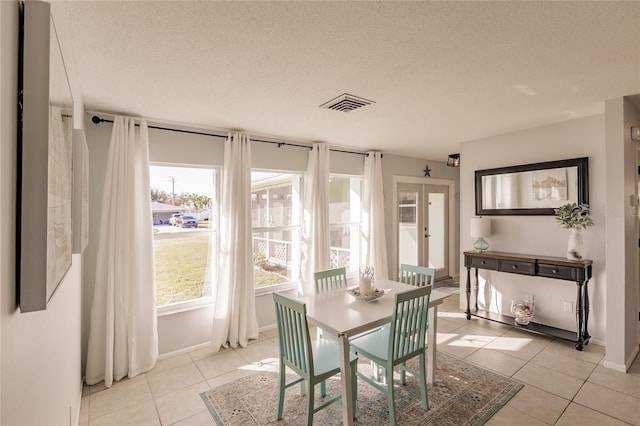 dining area featuring light tile patterned flooring, a textured ceiling, and french doors