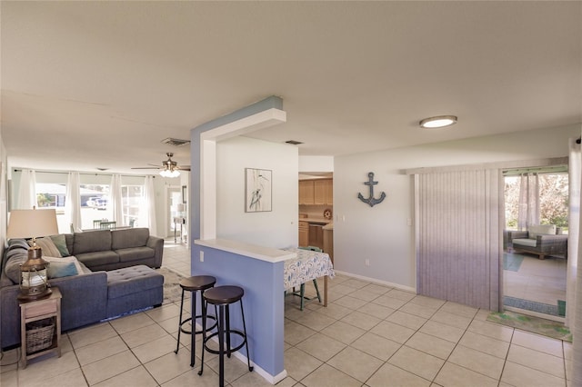 kitchen with light tile patterned floors, plenty of natural light, a breakfast bar, and ceiling fan