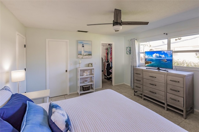 bedroom with light tile patterned flooring, a spacious closet, ceiling fan, and a closet