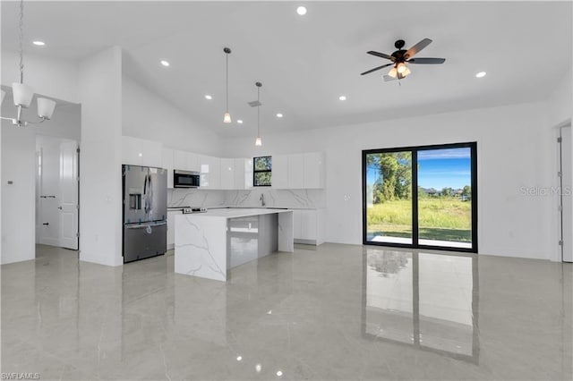 kitchen with decorative light fixtures, stainless steel appliances, a kitchen island, white cabinetry, and ceiling fan with notable chandelier