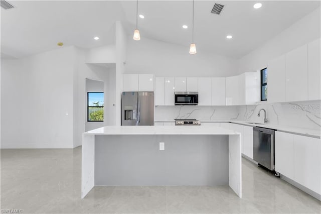 kitchen with hanging light fixtures, high vaulted ceiling, white cabinetry, appliances with stainless steel finishes, and sink