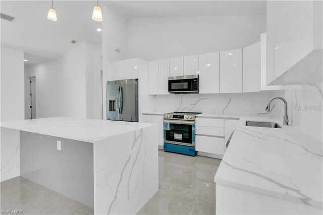 kitchen featuring decorative light fixtures, stainless steel appliances, a kitchen island, white cabinets, and sink