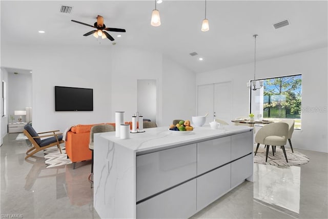 kitchen with decorative light fixtures, a kitchen island, ceiling fan, and white cabinetry