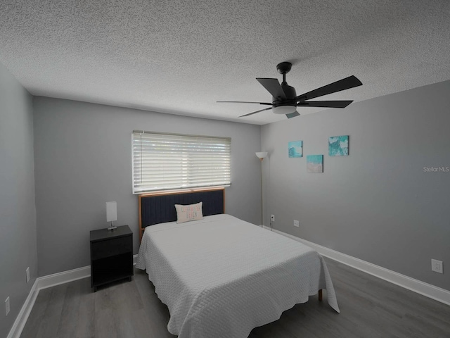 bedroom with ceiling fan, dark hardwood / wood-style floors, and a textured ceiling