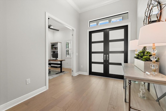 foyer with light hardwood / wood-style flooring, crown molding, and french doors