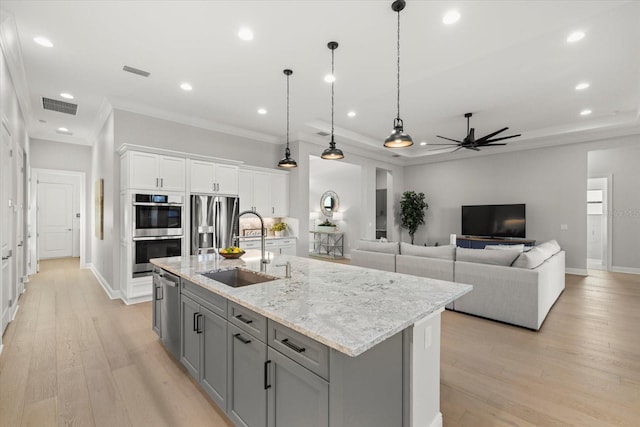 kitchen featuring white cabinets, sink, appliances with stainless steel finishes, and an island with sink