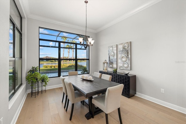 dining area featuring a water view, light hardwood / wood-style flooring, an inviting chandelier, and ornamental molding