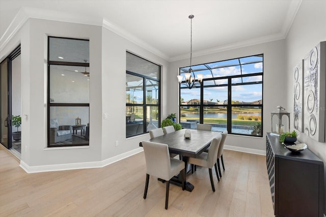 dining area featuring a water view, light wood-type flooring, crown molding, and a chandelier