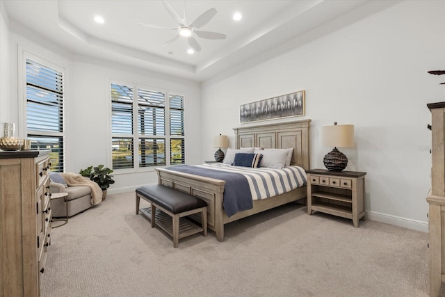 bedroom featuring light carpet, a tray ceiling, and ceiling fan