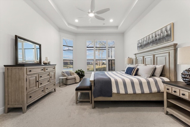 carpeted bedroom featuring ceiling fan and a tray ceiling