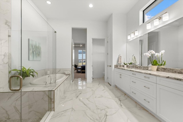 bathroom featuring tiled bath, vanity, and toilet