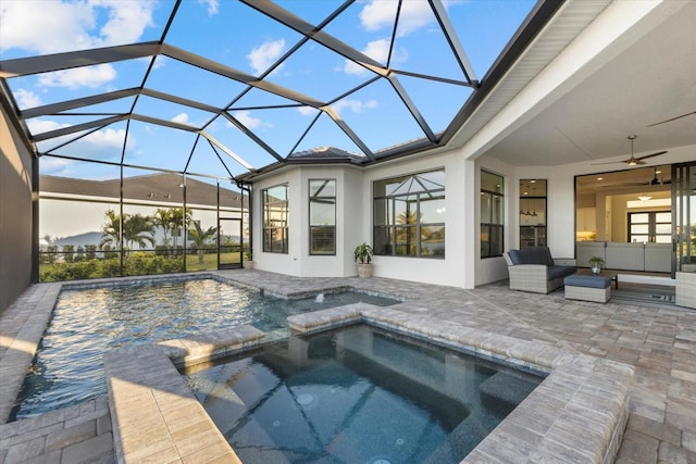 view of pool featuring an in ground hot tub, outdoor lounge area, ceiling fan, glass enclosure, and a patio