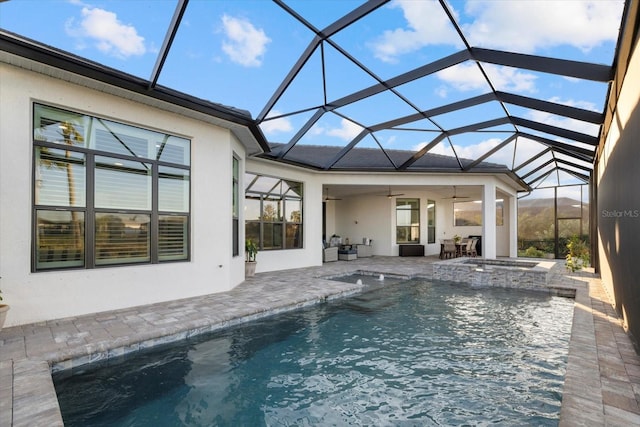 view of swimming pool with glass enclosure, ceiling fan, a patio, and an in ground hot tub