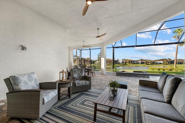 exterior space featuring an outdoor hangout area, a water view, glass enclosure, and ceiling fan