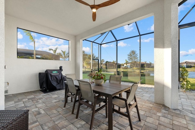 sunroom featuring ceiling fan and a water view