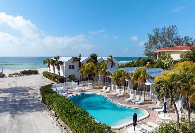 view of swimming pool with a water view, a patio, and a beach view