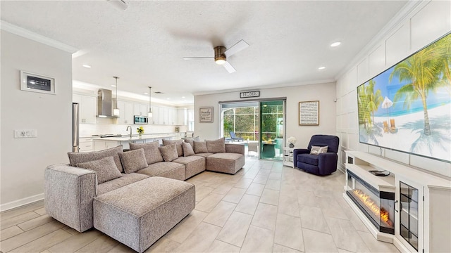 living room with a textured ceiling, ceiling fan, ornamental molding, and sink