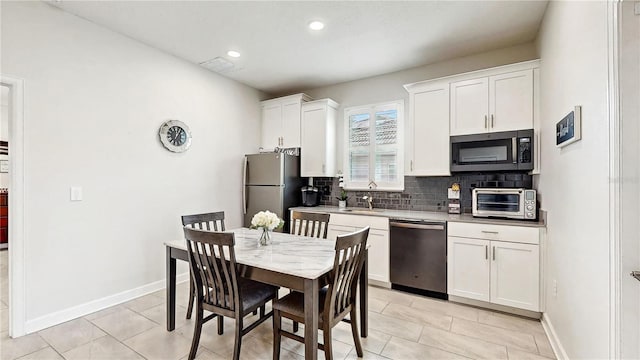 kitchen with decorative backsplash, appliances with stainless steel finishes, sink, light tile patterned floors, and white cabinets