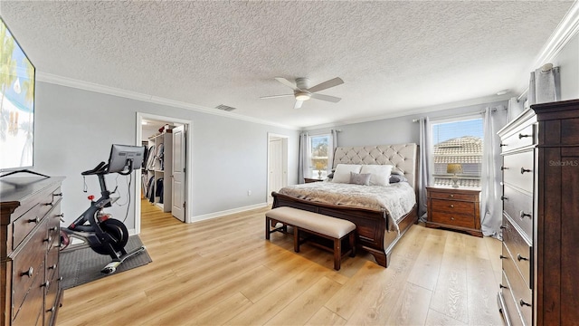 bedroom with a walk in closet, a closet, ceiling fan, and crown molding