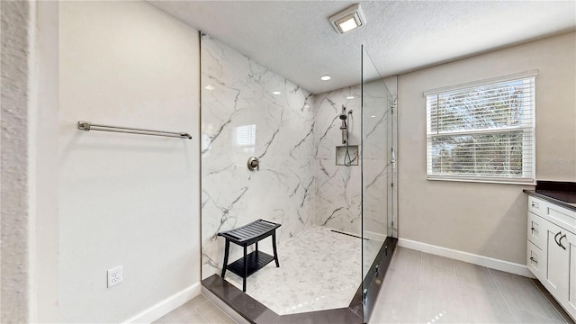 bathroom with tile patterned floors, vanity, a textured ceiling, and tiled shower