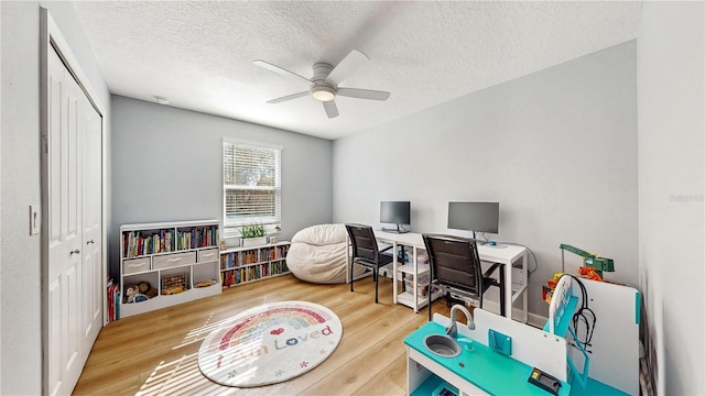 home office with hardwood / wood-style floors, ceiling fan, and a textured ceiling