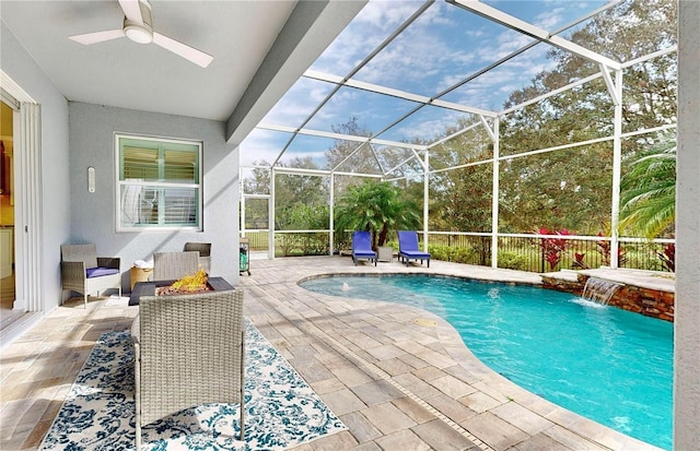 view of pool with pool water feature, ceiling fan, a patio area, and glass enclosure