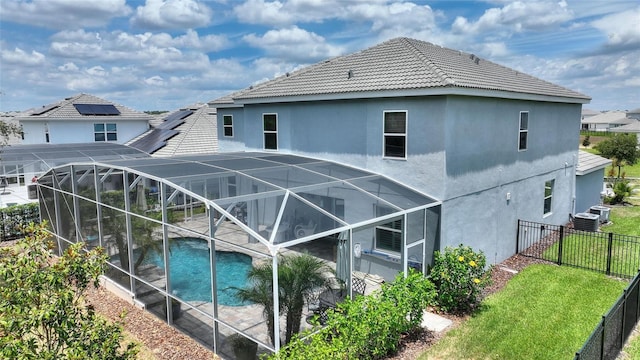 back of house with a yard, a fenced in pool, glass enclosure, and central AC unit