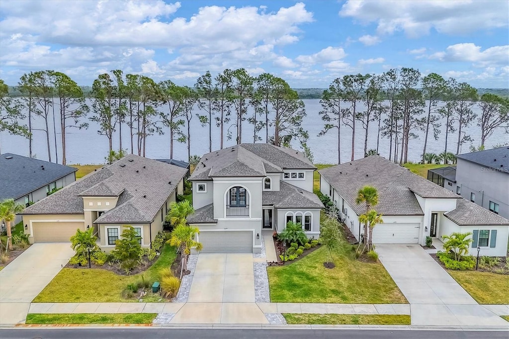 view of front of property with a front yard, a garage, and a water view