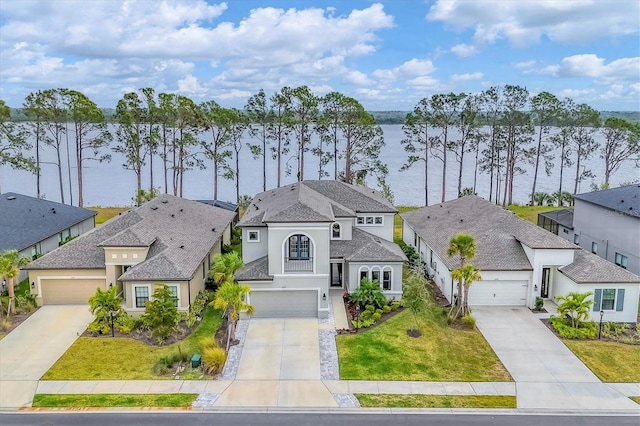 view of front of property with a front yard, a garage, and a water view