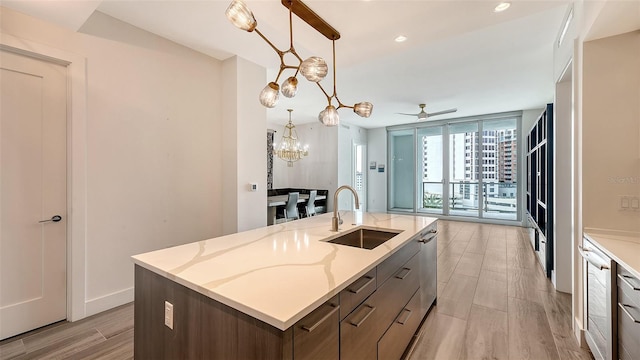 kitchen with a kitchen island with sink, a sink, decorative light fixtures, and dishwasher