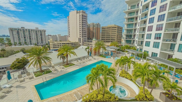 community pool featuring a patio area, a view of city, and fence