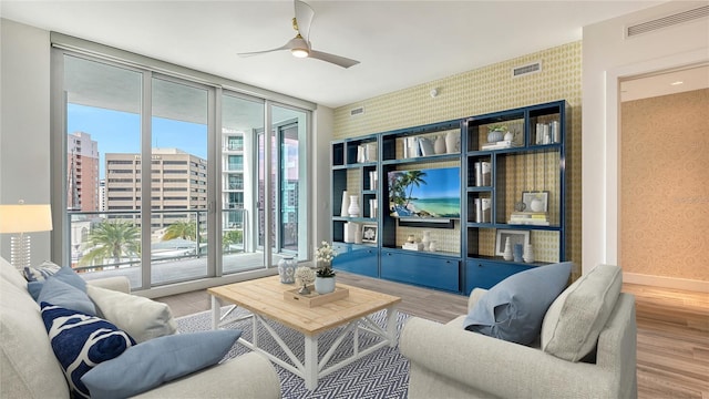 living area featuring a view of city, floor to ceiling windows, visible vents, wood finished floors, and wallpapered walls