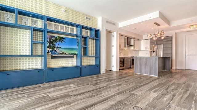 kitchen featuring stainless steel appliances, a kitchen island, light countertops, wall chimney exhaust hood, and decorative light fixtures