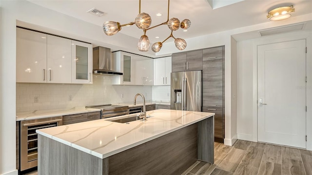 kitchen with wine cooler, stainless steel appliances, glass insert cabinets, modern cabinets, and wall chimney exhaust hood