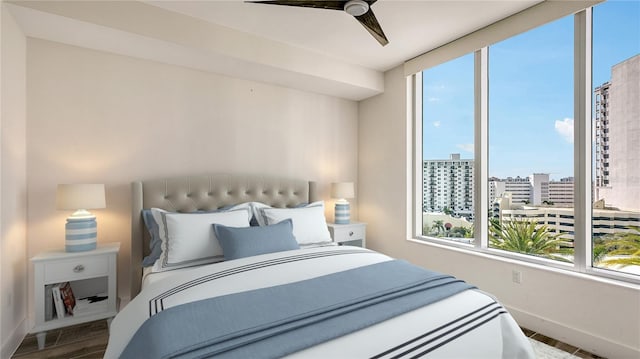 bedroom featuring baseboards, multiple windows, wood finished floors, and a city view