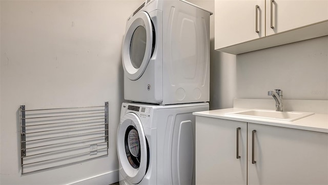 washroom featuring stacked washer / dryer, cabinet space, and a sink