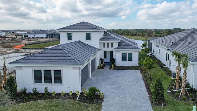 view of front of house with cooling unit, a garage, and a water view