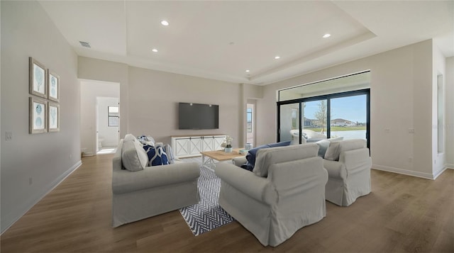 living room featuring a raised ceiling and light hardwood / wood-style flooring