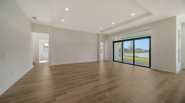 unfurnished room featuring a raised ceiling and hardwood / wood-style flooring