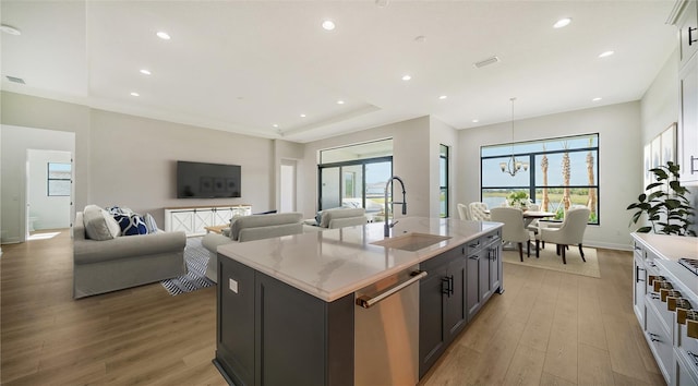 kitchen with dishwasher, a center island with sink, a wealth of natural light, sink, and light hardwood / wood-style flooring