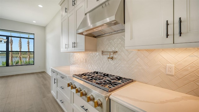 kitchen featuring light stone counters, light hardwood / wood-style flooring, decorative backsplash, and white cabinetry