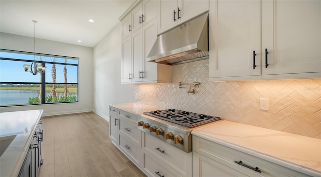 kitchen with white cabinets, stainless steel gas cooktop, light stone counters, and a water view